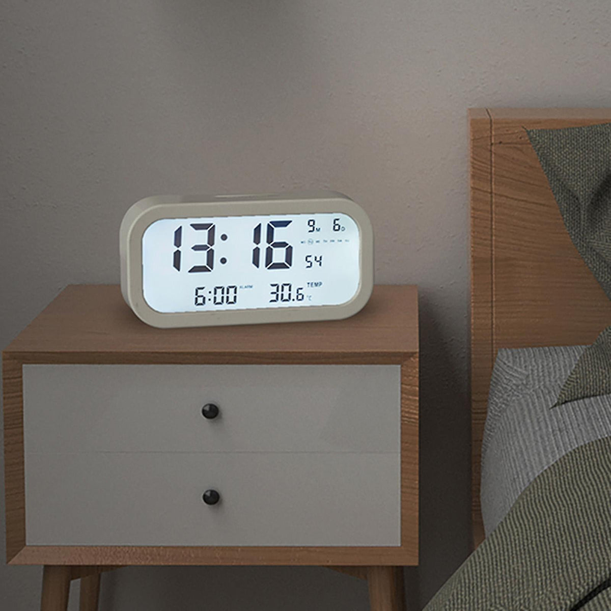 Beli digitalni budilnik sa pozadinskim osvetljenjem ekrana.