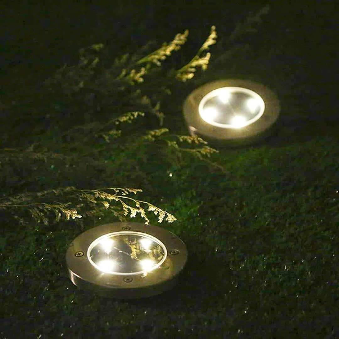 Solarna lampa u obliku okruglog diska sa nosačem za zemlju.