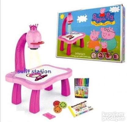 Roze kreativni set obuhvata stolić, projektor i pribor za crtanje.