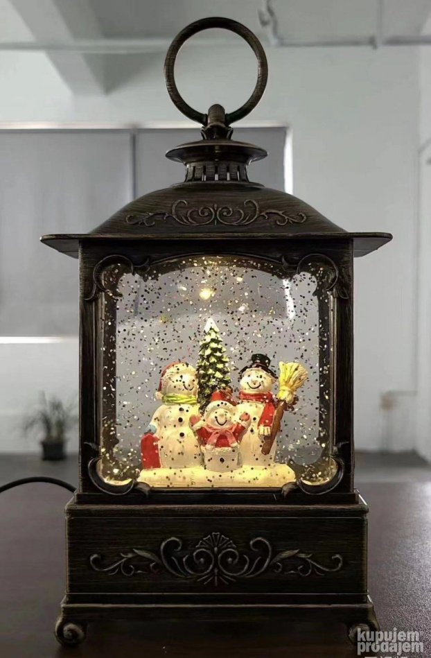 Novogodišnji ukras u obliku lampe prikazuje Deda Mraza sa jelkom.
